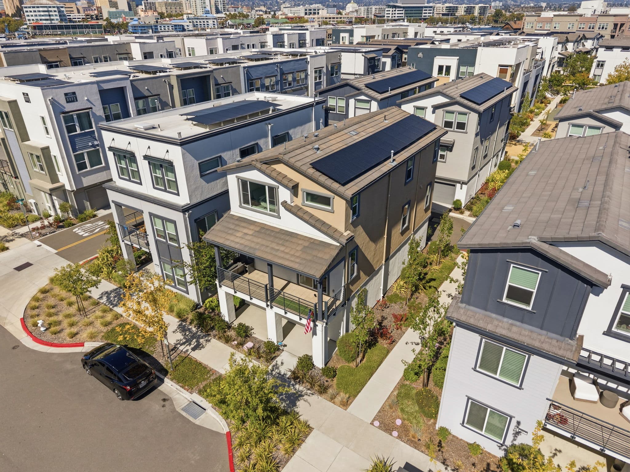 Aerial over the home — owned rooftop solar, covered balcony, and downtown Oakland on the horizon